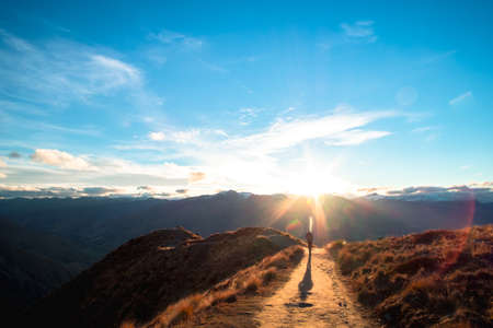 A hiker hiking on the beautiful track with a landscape of the mountains and Lake Wanaka. Roys Peak Track, South Island, New Zealand.