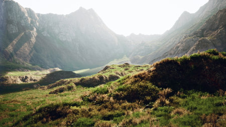Lush green hills cradle a serene valley surrounded by towering mountains. The golden light of sunrise casts a magical glow, revealing natures beauty in this tranquil landscape.