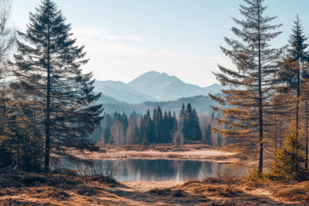 Calm waters of a lake reflect surrounding mountains under a clear blue sky. Tall evergreen trees frame the peaceful view showcasing nature's beauty in early springtime.