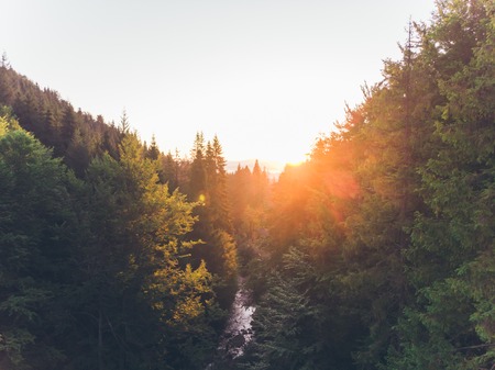 aerial view of sunset over mountains with forest and river. summer time