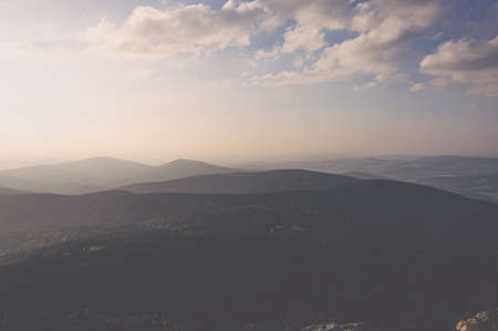 Cloudy sky and forests in the valley in the rays of sunset